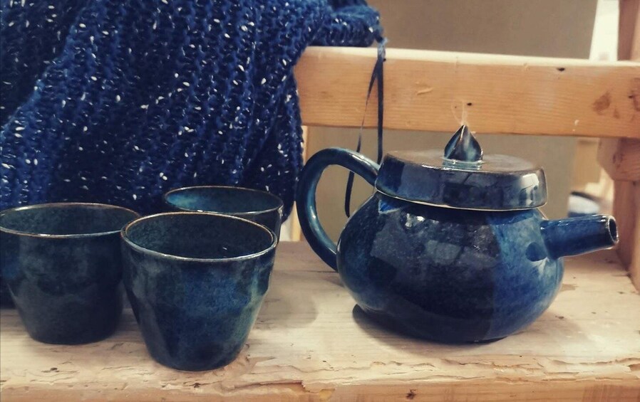 A blue teapot and three matching cups on a wooden surface. 3