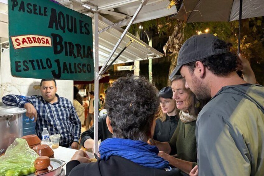 A street food stall with a sign listing dishes like 'AQUIES' and 'JALISCO.' 5