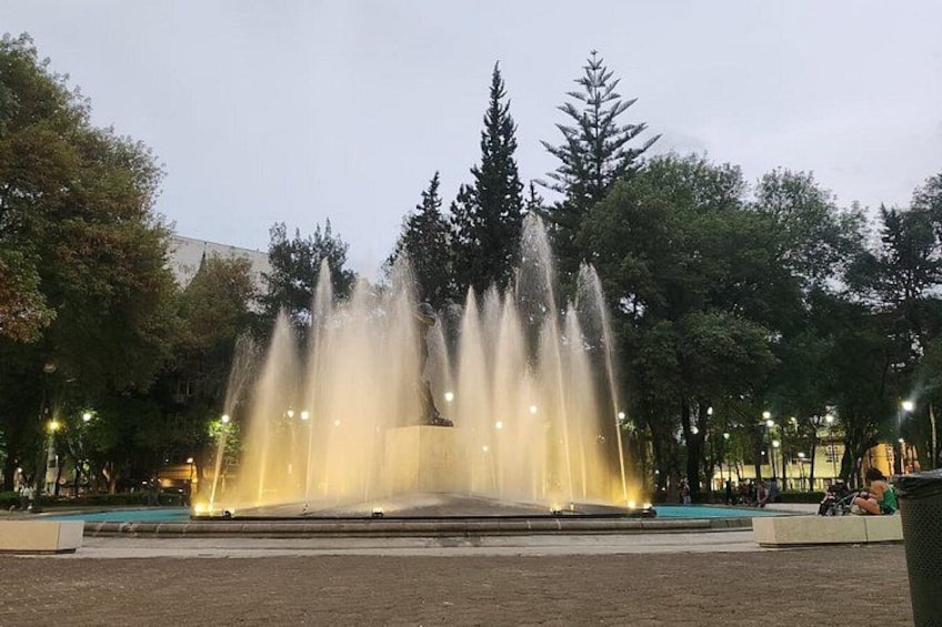 A fountain with water jets in a park at dusk. 2
