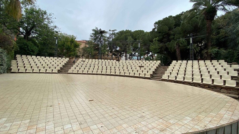 An outdoor amphitheater with tiered seating and a tiled stage area. 2