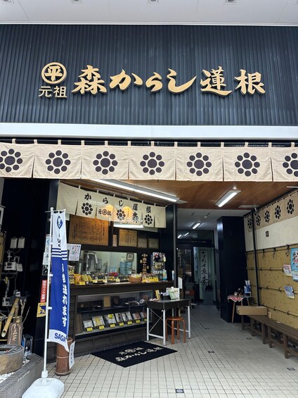 A storefront with a dark facade and a sign with Japanese characters. There are paw print decorations on the awning, and a display counter with various items. 4