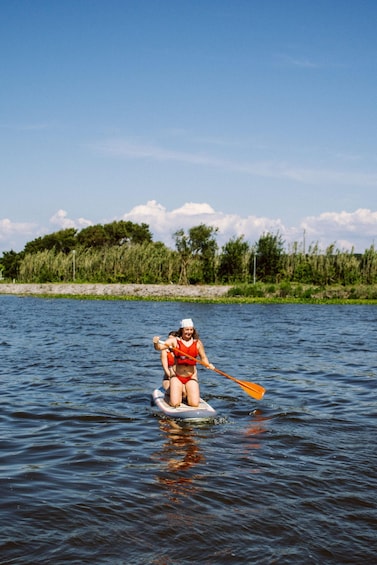 A person paddleboarding on a calm river with greenery and trees in the background. 3