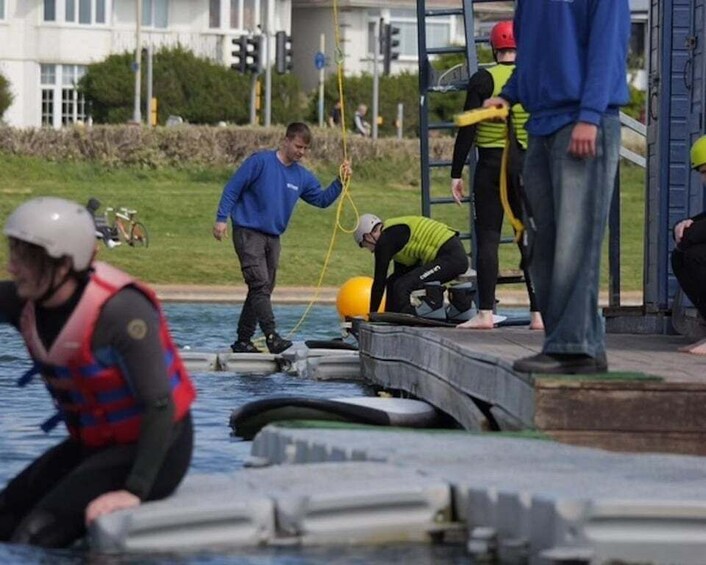 People in life vests near a water body, some on a platform, and one person in the water. 2
