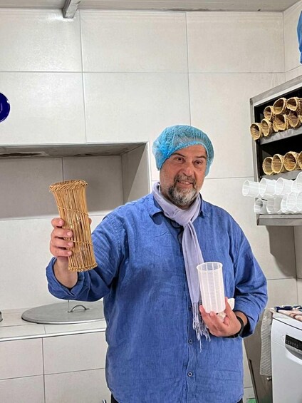 A person holding a bundle of straw and a plastic container in a kitchen. 4