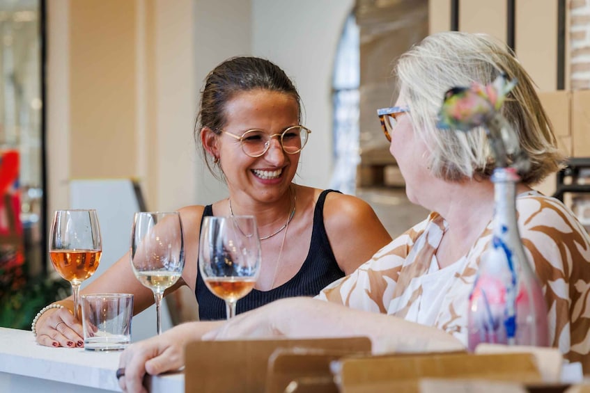 Two people sitting at a table with wine glasses. 1
