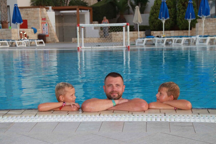 A swimming pool with a goalpost, lounge chairs, and umbrellas. 5