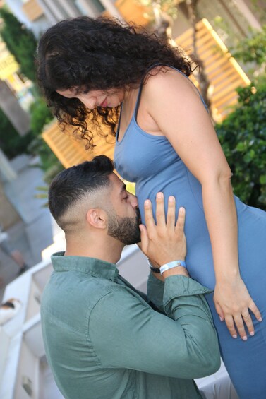 A couple embracing, with the man kissing the woman's pregnant belly. 1