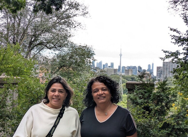 Two people standing in a park with a city skyline in the background. 4