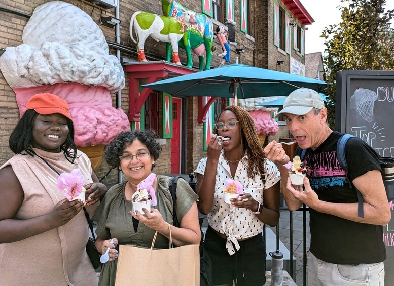People enjoying ice cream cones in front of a building with colorful decorations and a large ice cream sculpture. 1