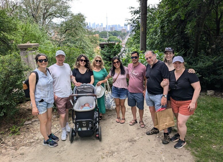 A group of people standing on a dirt path in a park with trees and a city skyline in the background. 3