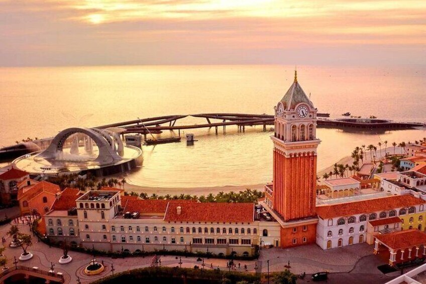 A coastal cityscape with a prominent clock tower, a modern bridge, and historic buildings. 4