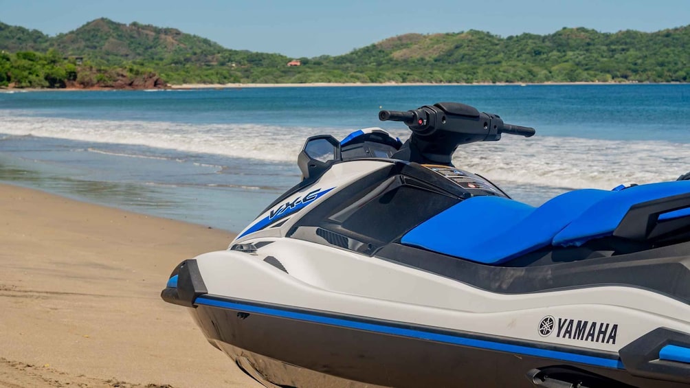 A Yamaha jet ski on a beach with a view of the ocean and hills in the background. 3