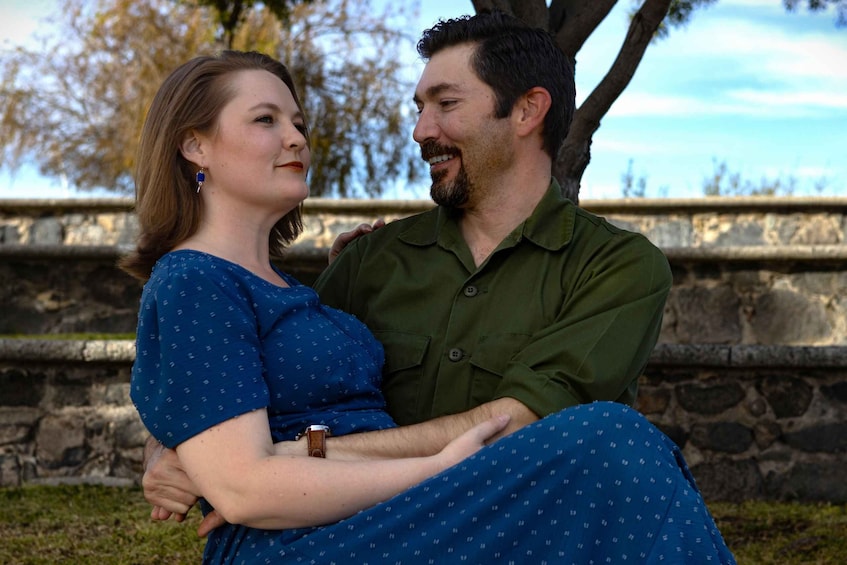 A couple sitting on a stone bench outdoors with trees in the background. 1