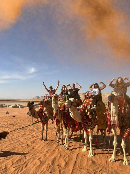 A group of people riding camels in a desert with a clear sky. 5