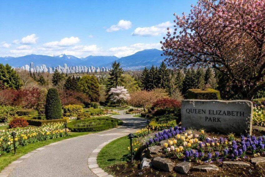 Queen Elizabeth Park with a sign, a pathway, and colorful flowers. 5