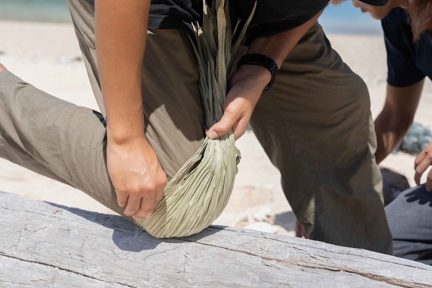 A person handling a woven mat on a wooden surface. 2