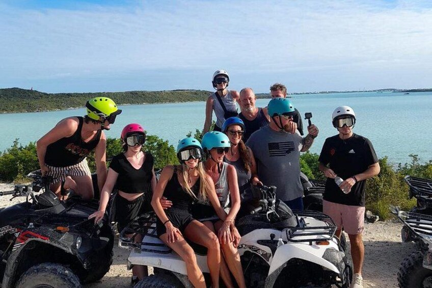 A group of people on ATVs by a lake with a clear sky. 2