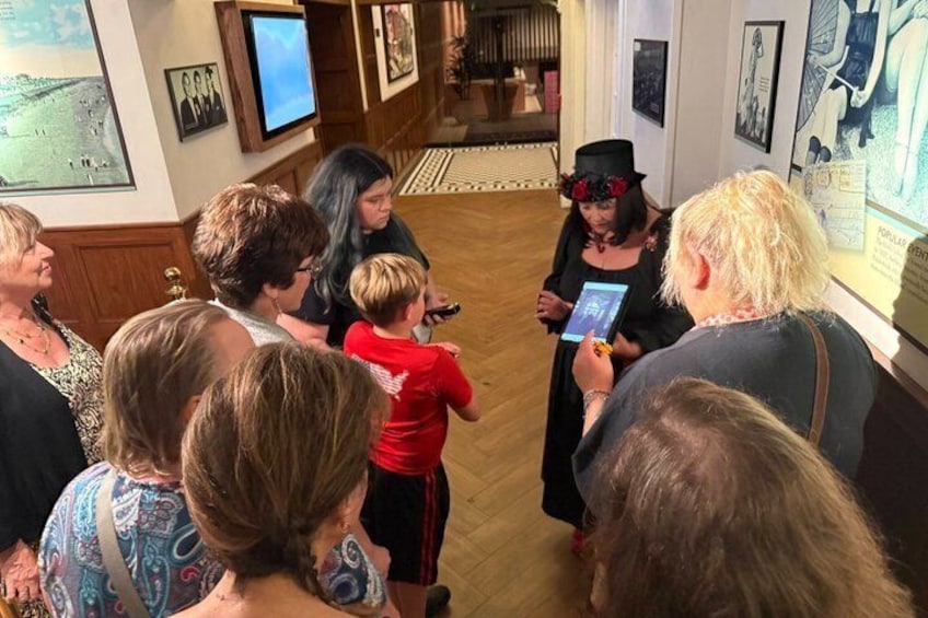 A group of people in an indoor museum or gallery, examining exhibits and a digital display. 4