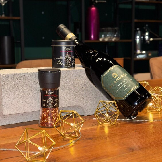 A bottle of Hungarian wine, a spice container, and decorative geometric lights on a table. 3