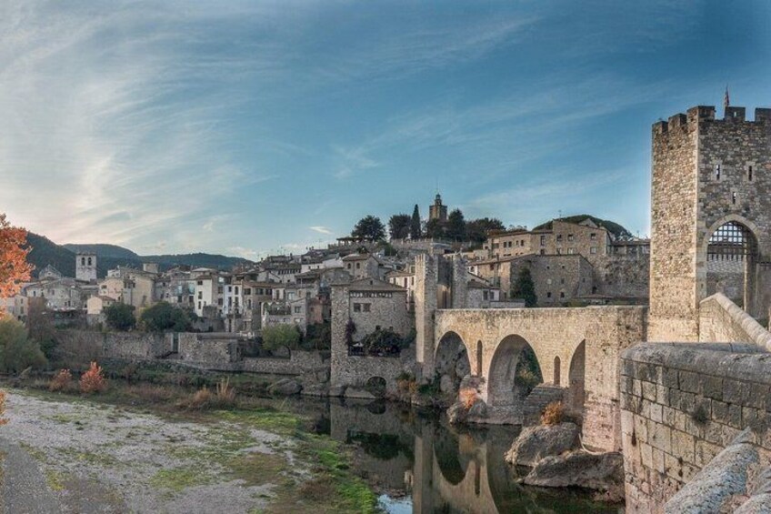 A historic town with stone bridges, a castle, and a river. 2