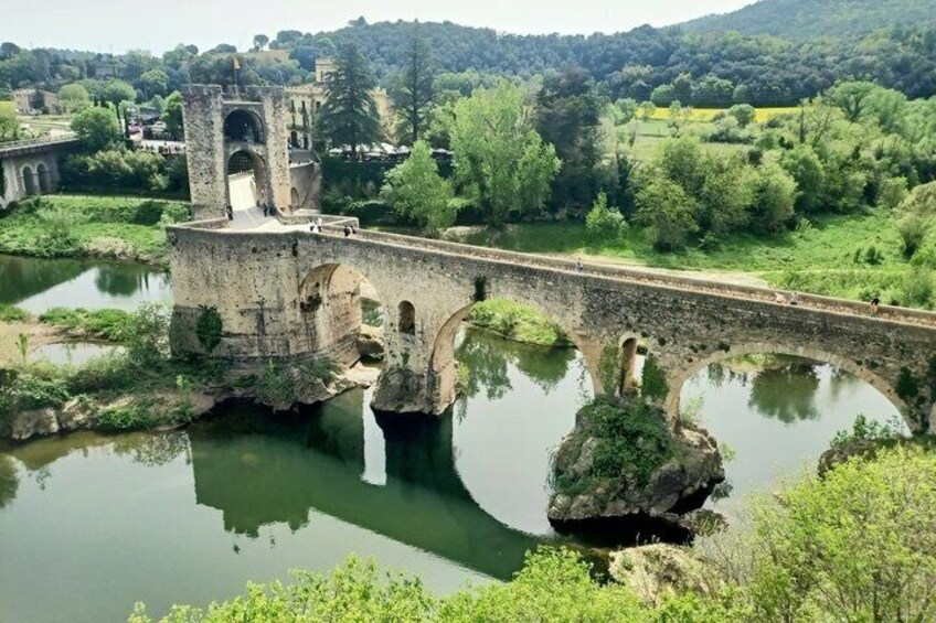 A stone bridge over a river with a small tower and arches. 1