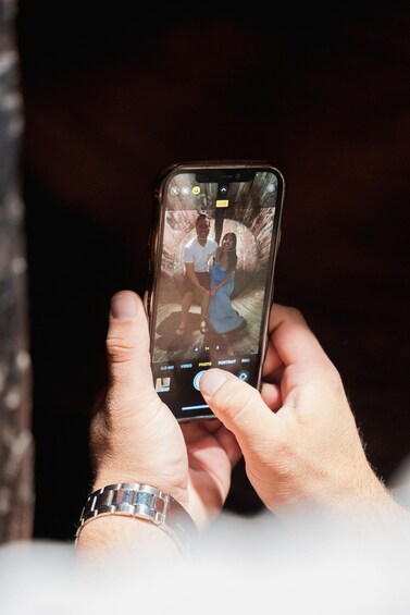 A person holding a smartphone with a photo of two people on the screen. 2