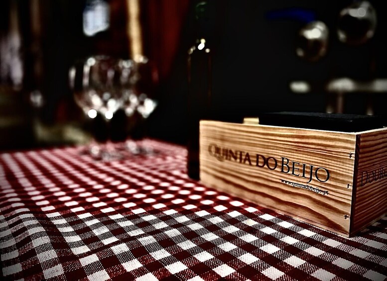 A wooden box labeled 'QUINIA DO BEJO' on a checkered tablecloth. 5