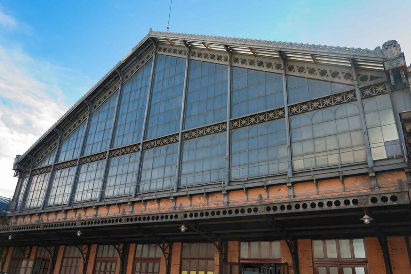 A large building with ornate brickwork, large glass windows, and decorative metalwork. 4