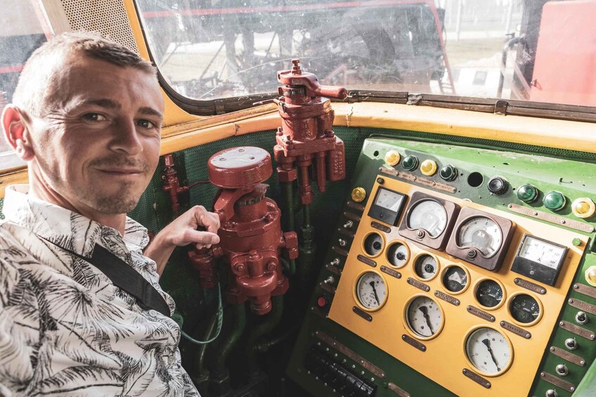 A person in a vehicle's control panel with various gauges and a red valve. 2