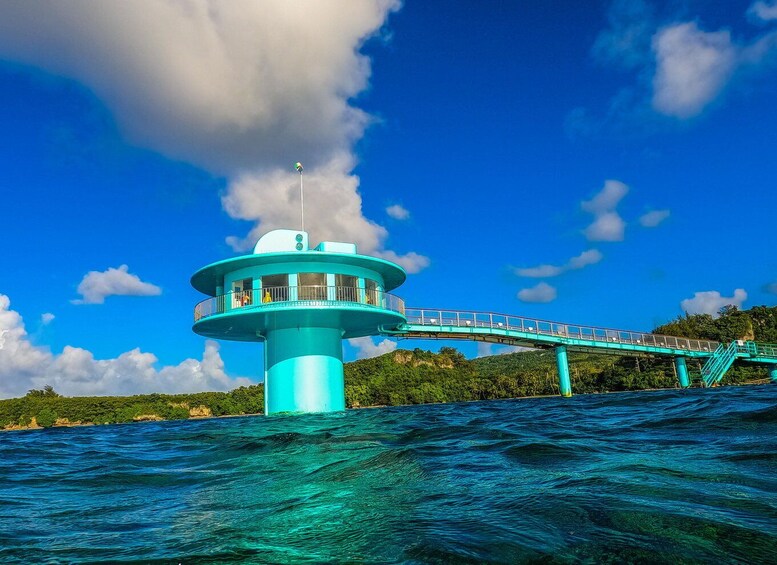 A turquoise lighthouse with a walkway on a clear day. 5