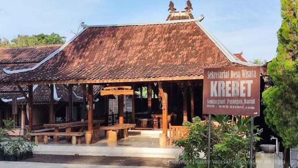 A traditional wooden building with a tiled roof, a signboard, and outdoor seating. 3