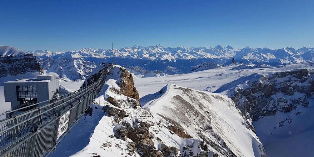 A snow-covered mountain landscape with a suspension bridge and a clear blue sky. 1