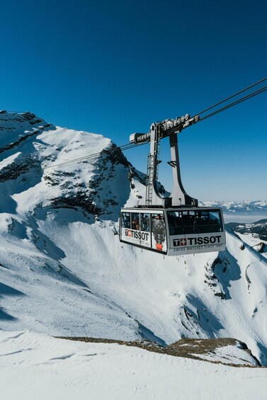 A Tissot branded cable car ascending a snow-covered mountain. 3
