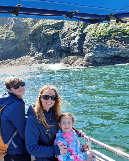 Three people on a boat with a rocky coastline in the background. 5