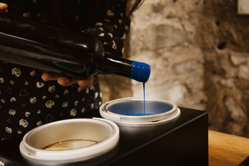 A person pouring a dark liquid from a bottle into a container. 1