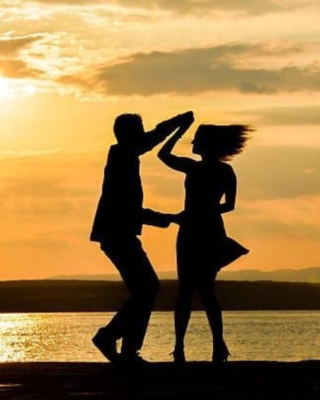 A silhouette of a couple dancing against a sunset by a body of water. 1