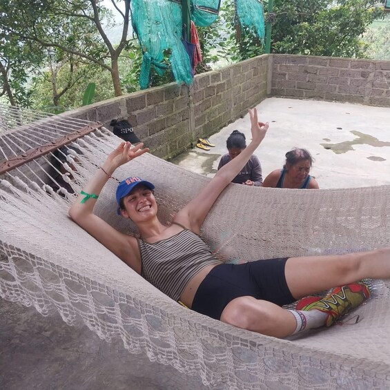 A person relaxing in a hammock on a concrete platform with a brick wall and trees in the background. 3