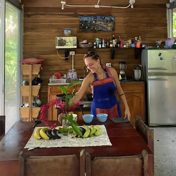 A person arranging bananas and flowers on a table in a kitchen. 1