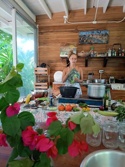 A person cooking with vegetables and pots on a wooden table in a kitchen with a wooden wall and a window. 4