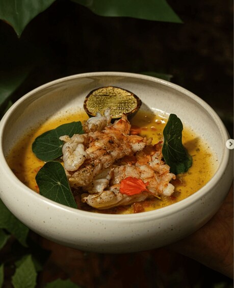 A bowl of shrimp with herbs and a slice of lemon. 5