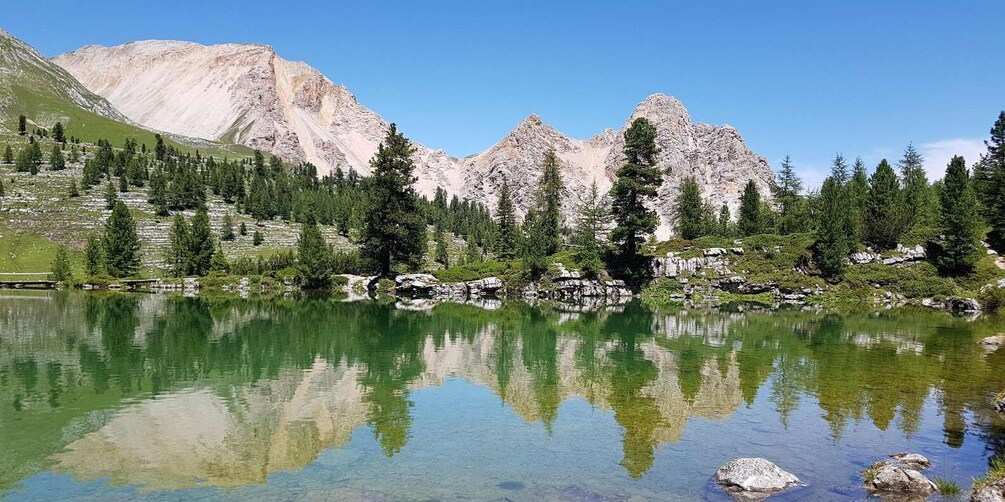 A mountain lake with clear reflections, surrounded by rocky mountains and evergreen trees. 1
