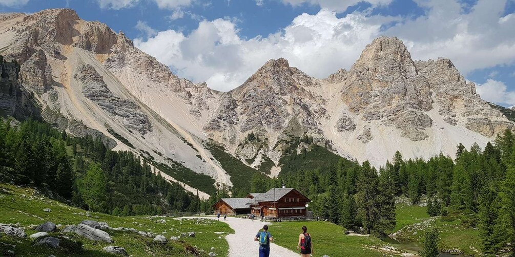 A mountain lodge with a clear path leading to it, surrounded by forested slopes and rocky peaks. 3