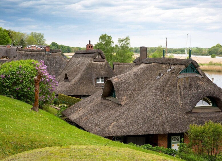 Thatched-roof cottages with a river in the background. 2