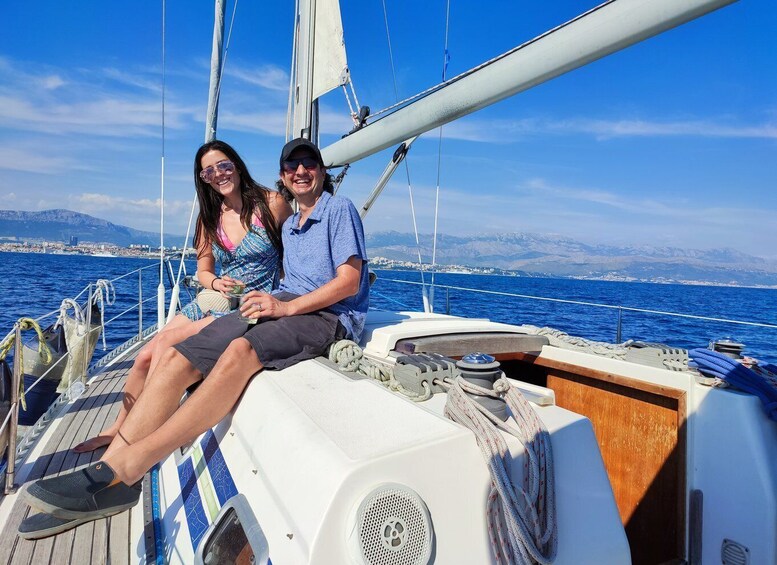 A couple on a sailboat with a cityscape and mountains in the background. 5