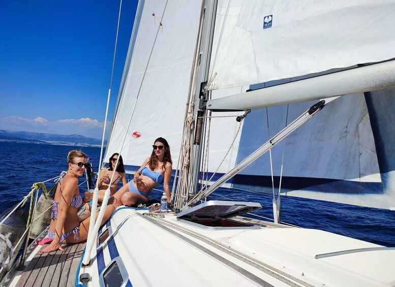 Three people on a sailboat with a clear blue sky and calm sea. 2