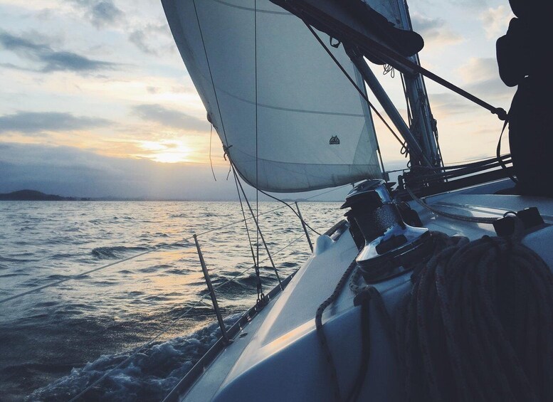 A sailboat with a white sail on a body of water during sunset. 1