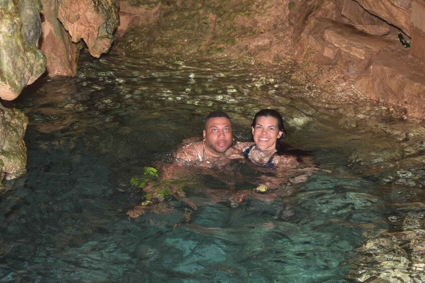Two people in a clear, rocky water body. 1