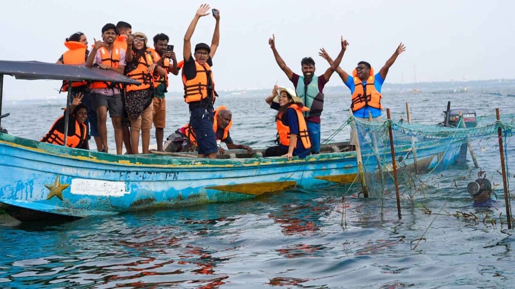 A group of people on a small boat wearing life jackets, with one person raising their hand. 1
