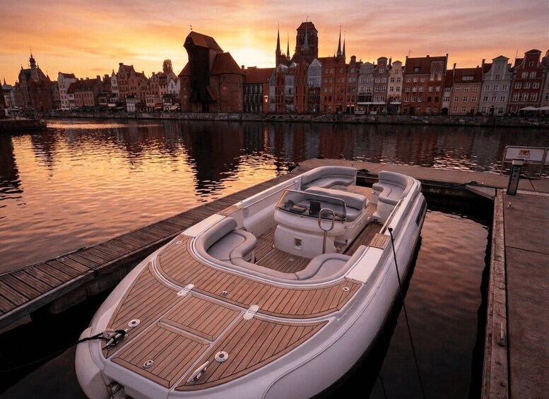 A boat docked at a pier with a city skyline in the background during sunset. 2