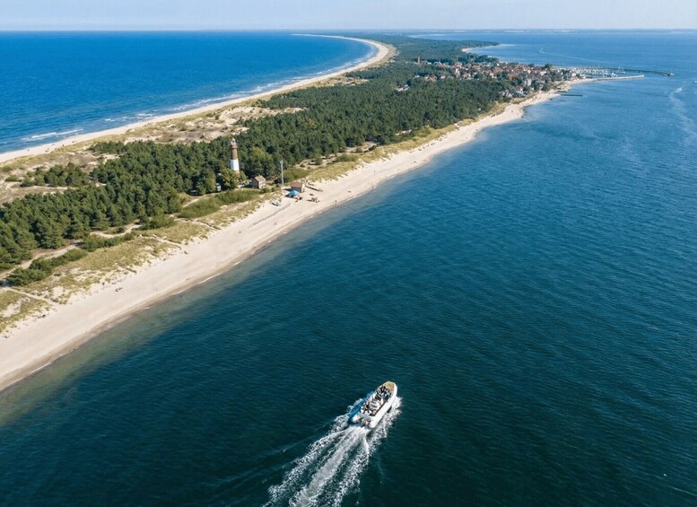 An aerial view of a coastal area with a lighthouse, beach, and a boat on the water. 3